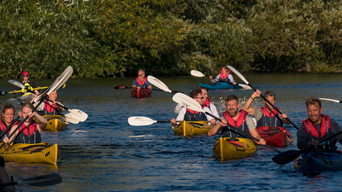 Svenskar paddlar kajak i samband med en träff i naturen.