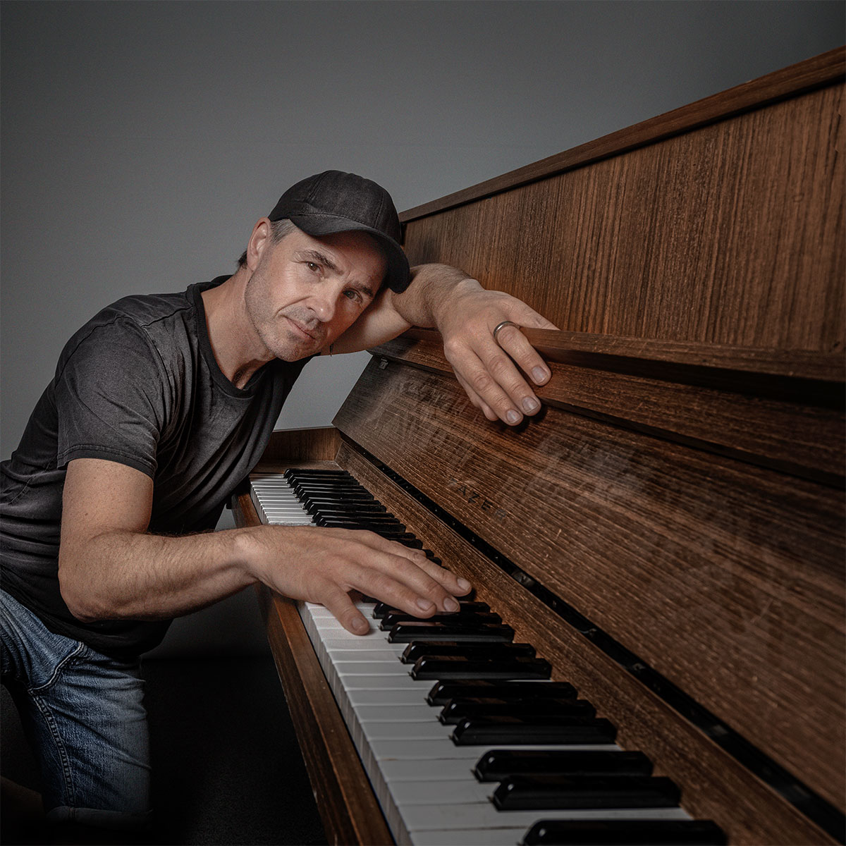 Peter Jöback lutad över ett piano, fotograferad av Niklas Palmklint