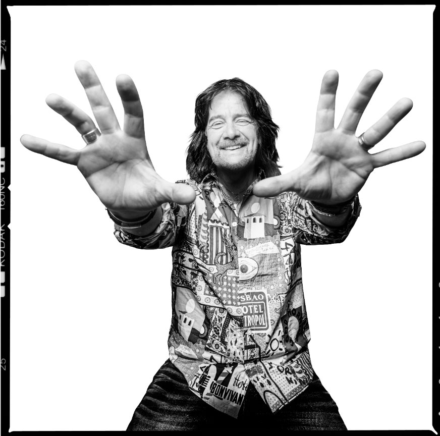 Robert Wells i svartvitt porträtt med händerna utsträckta mot kameran, fotograferad av Niklas Palmklint