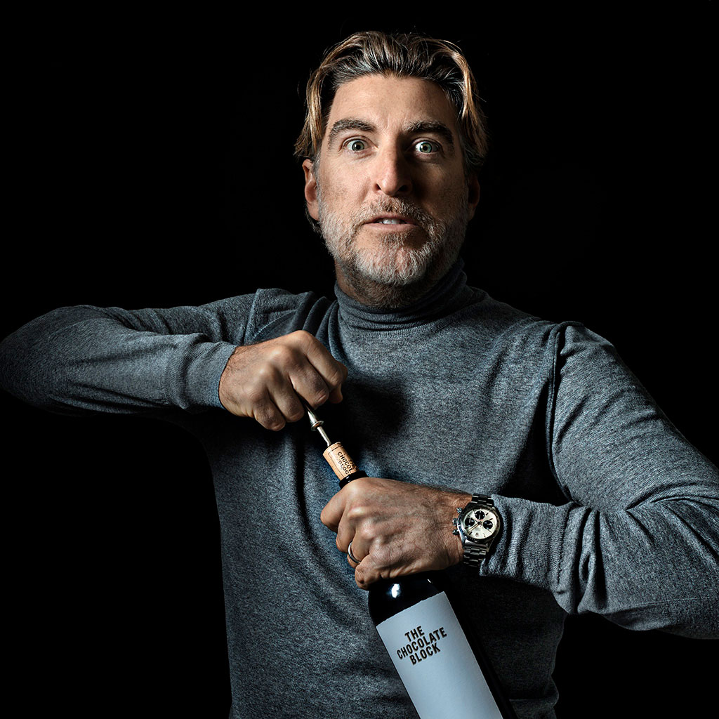 Peter Stern öppnar en vinflaska i ett mörkt porträtt, fotograferad av Niklas Palmklint