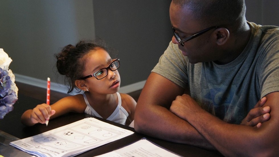 Liten flicka gör hemläxorna med pappa